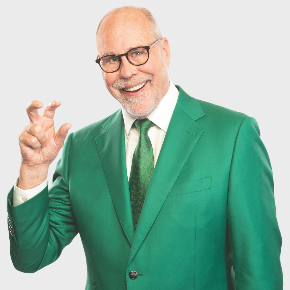 Dr. Neal Smatresk wearing a green suit holding up his right hand in the shape of a claw representing the University of North Texas