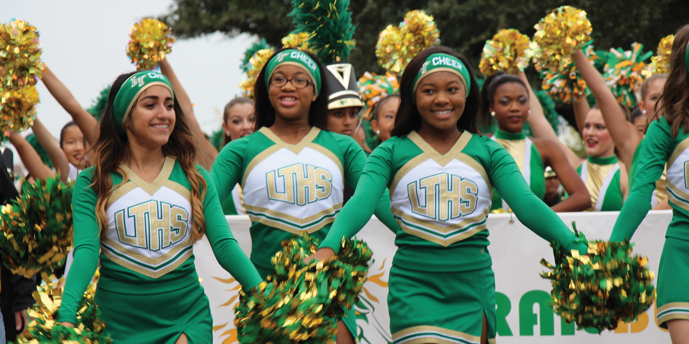 Lebanon Trail High School cheerleaders smiling with pom poms walking in a parade