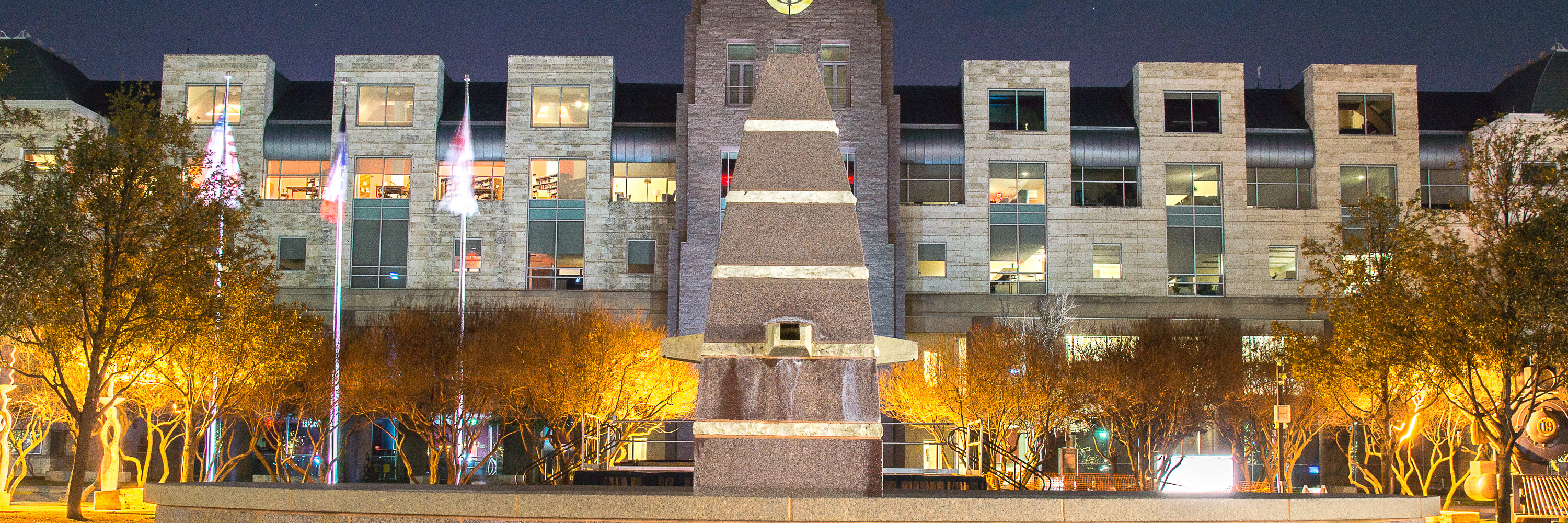 A fountain is lit up in front of City Hall at night time.