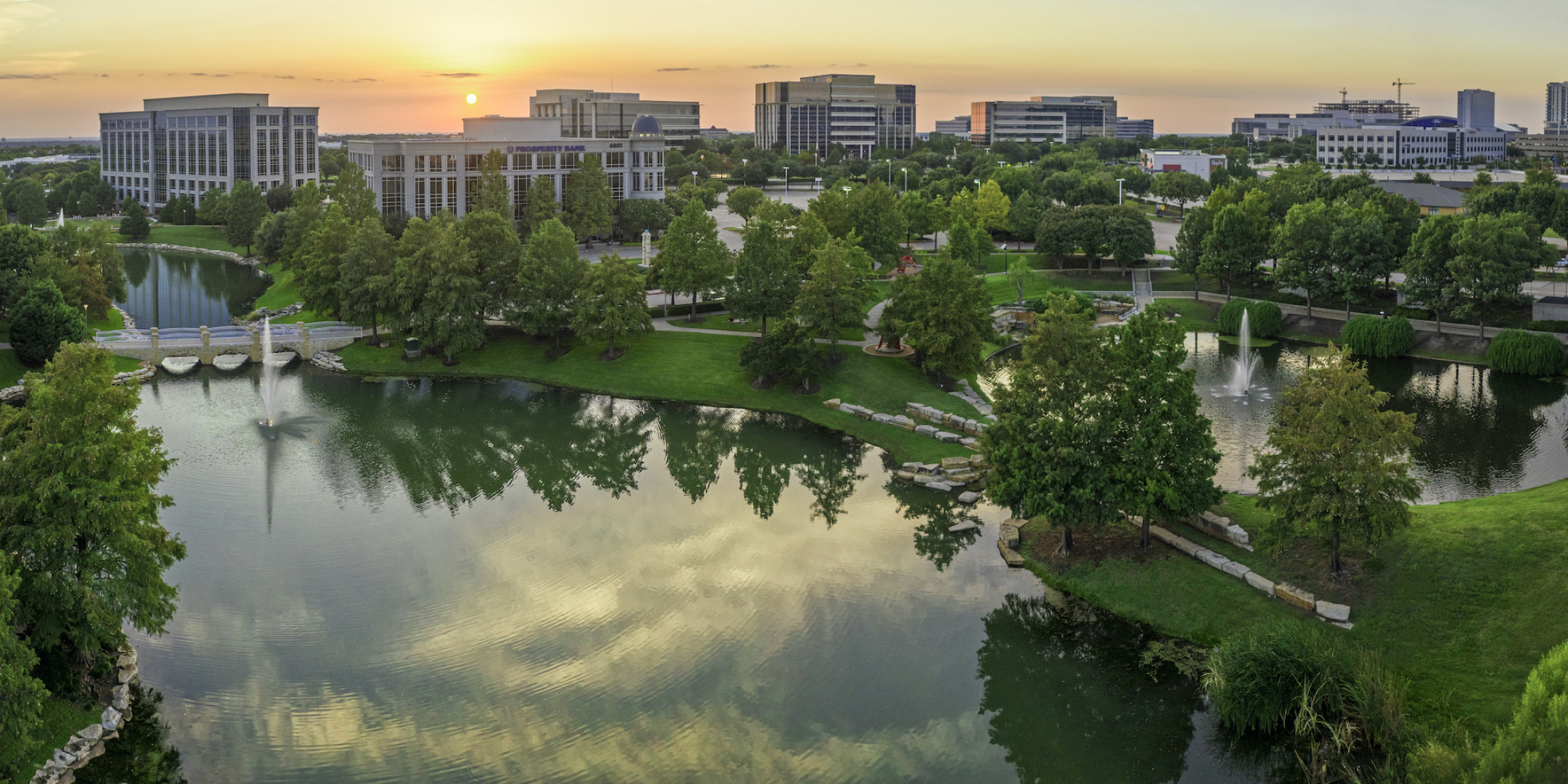 Aerial shot of office buildings, ponds and sidewalks at Hall Park. The photo was taken at sunset.