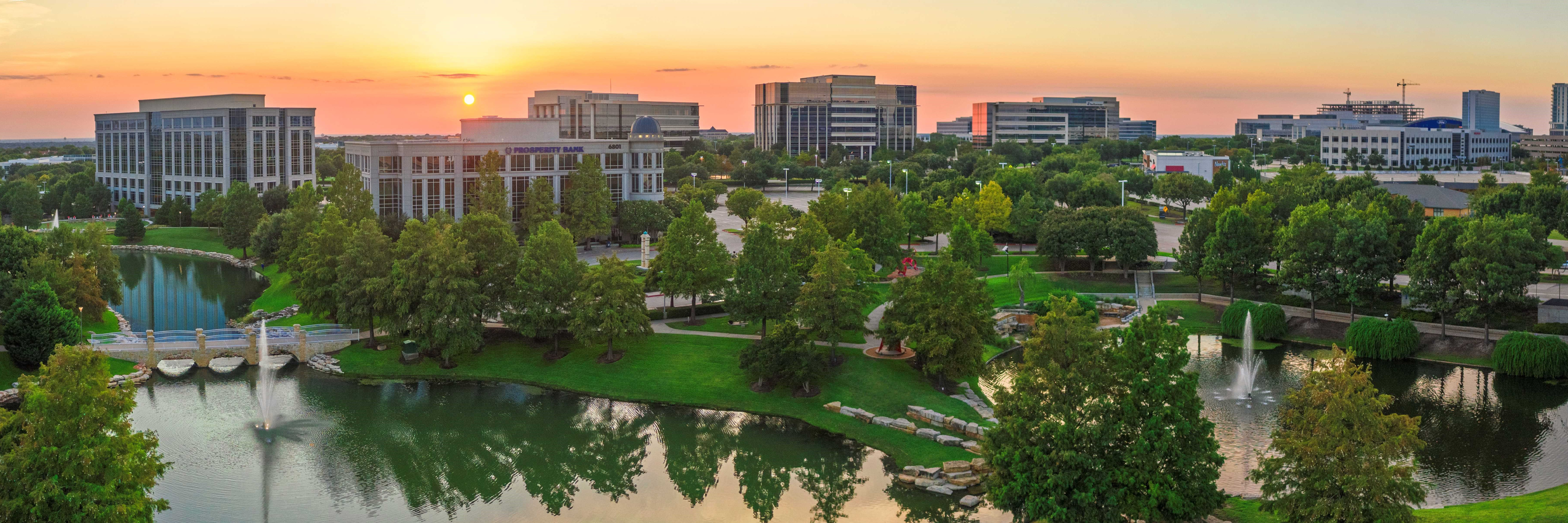 Aerial shot of office buildings, ponds and walking trails at Hall Park. The photo was taken at sunset.