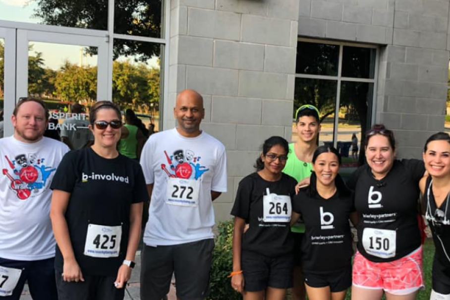 Competitors in the Frisco Arts 5 k gather for a picture. They wear their race numbers on their shirt.