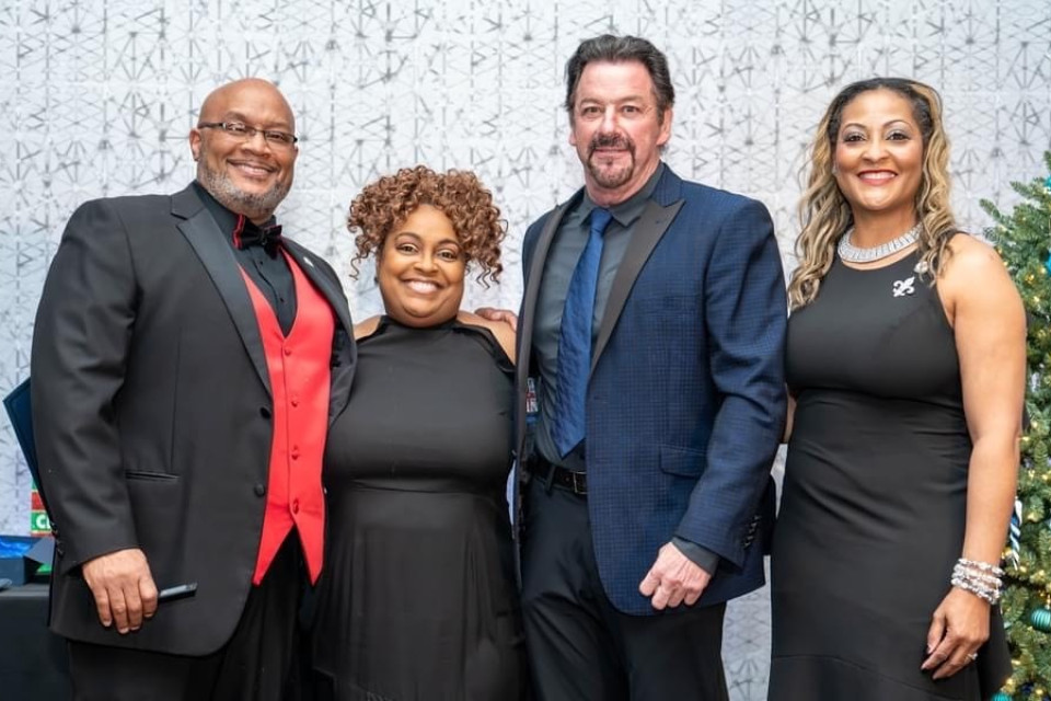 Four adults gather for a photo at an event for the Collin County Black Chamber of Commerce.