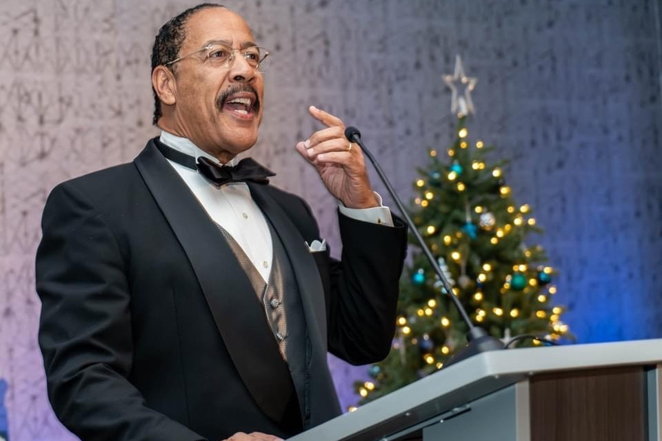 A man speaks into a microphone at the podium at an event.