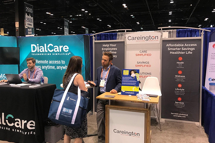 A Careington representative speaks with an event attendee at a show booth.