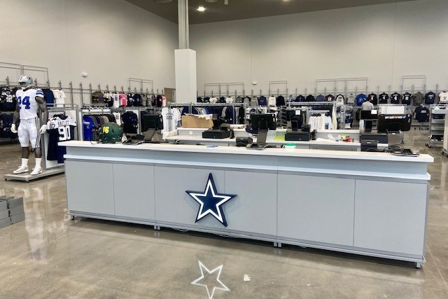 Large store with racks of Dallas Cowboys merchandise and a checkout counter with cash registers