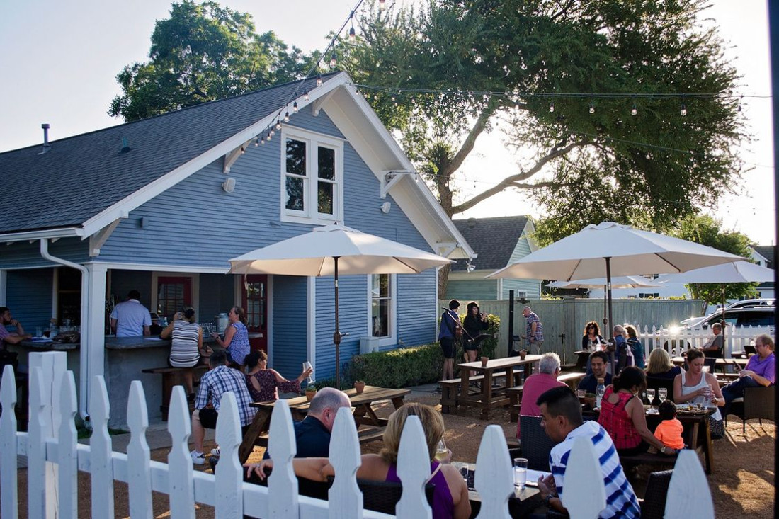 Patio with tables, a bar and live music at Eight 11 Wine Bar.