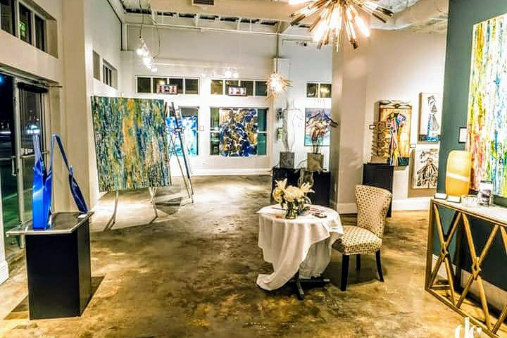 Inside an art gallery. There are paintings on the walls and on easels.