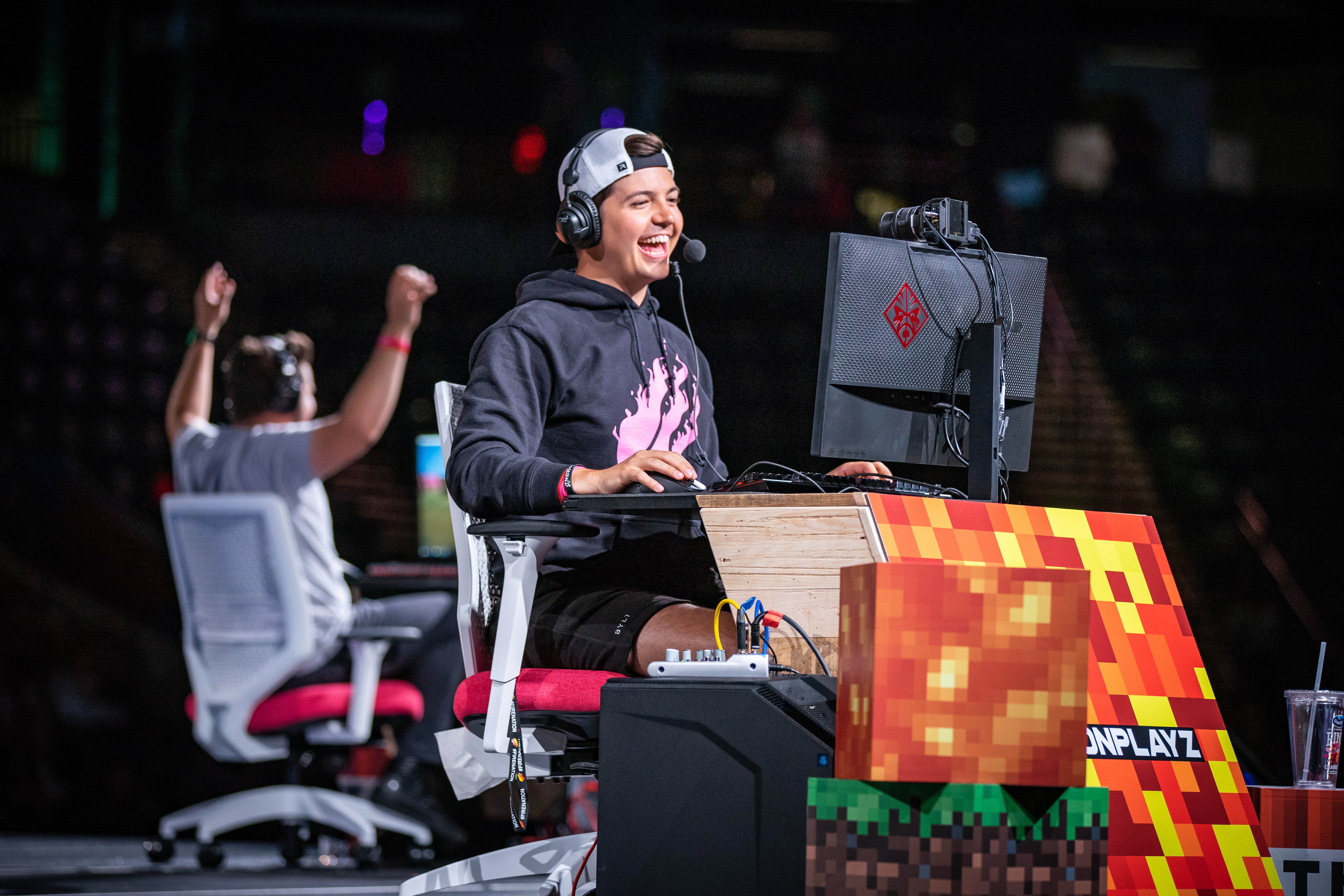 A man plays video games on his computer on a stage at a gaming event.