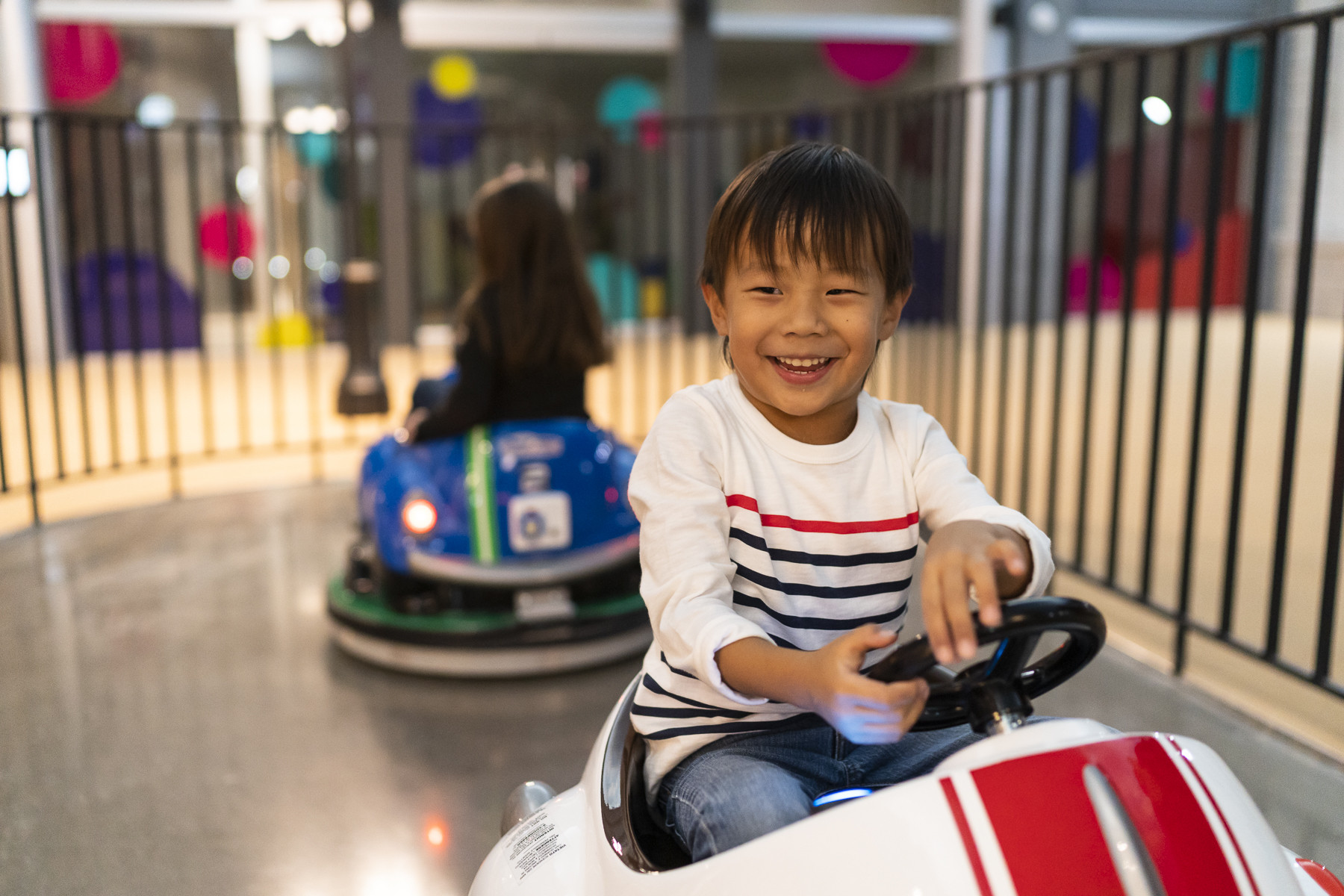 A small boy rides a miniature car indoors at KidZania.