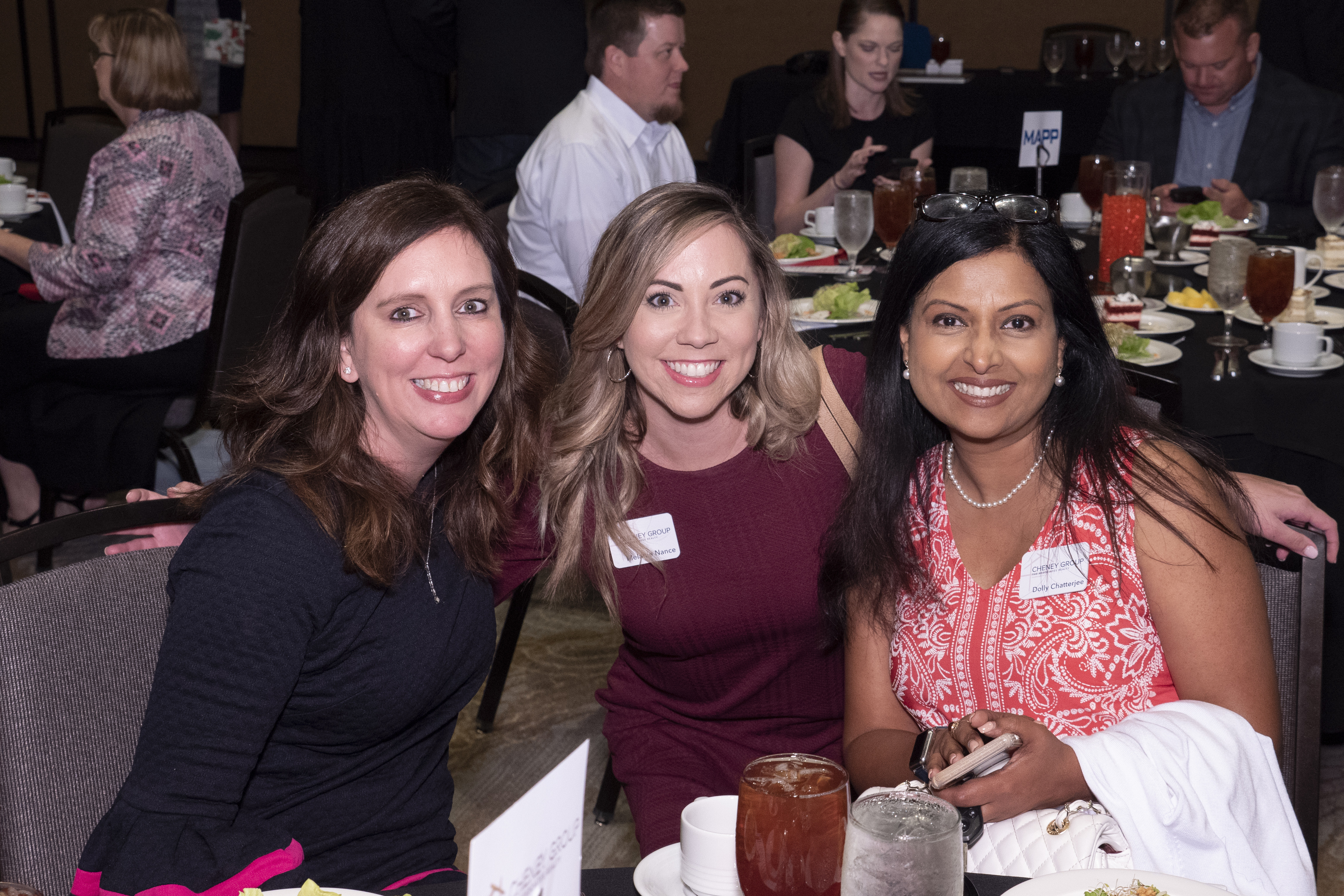 Three ladies sitting in chairs gather for a photo at an event.