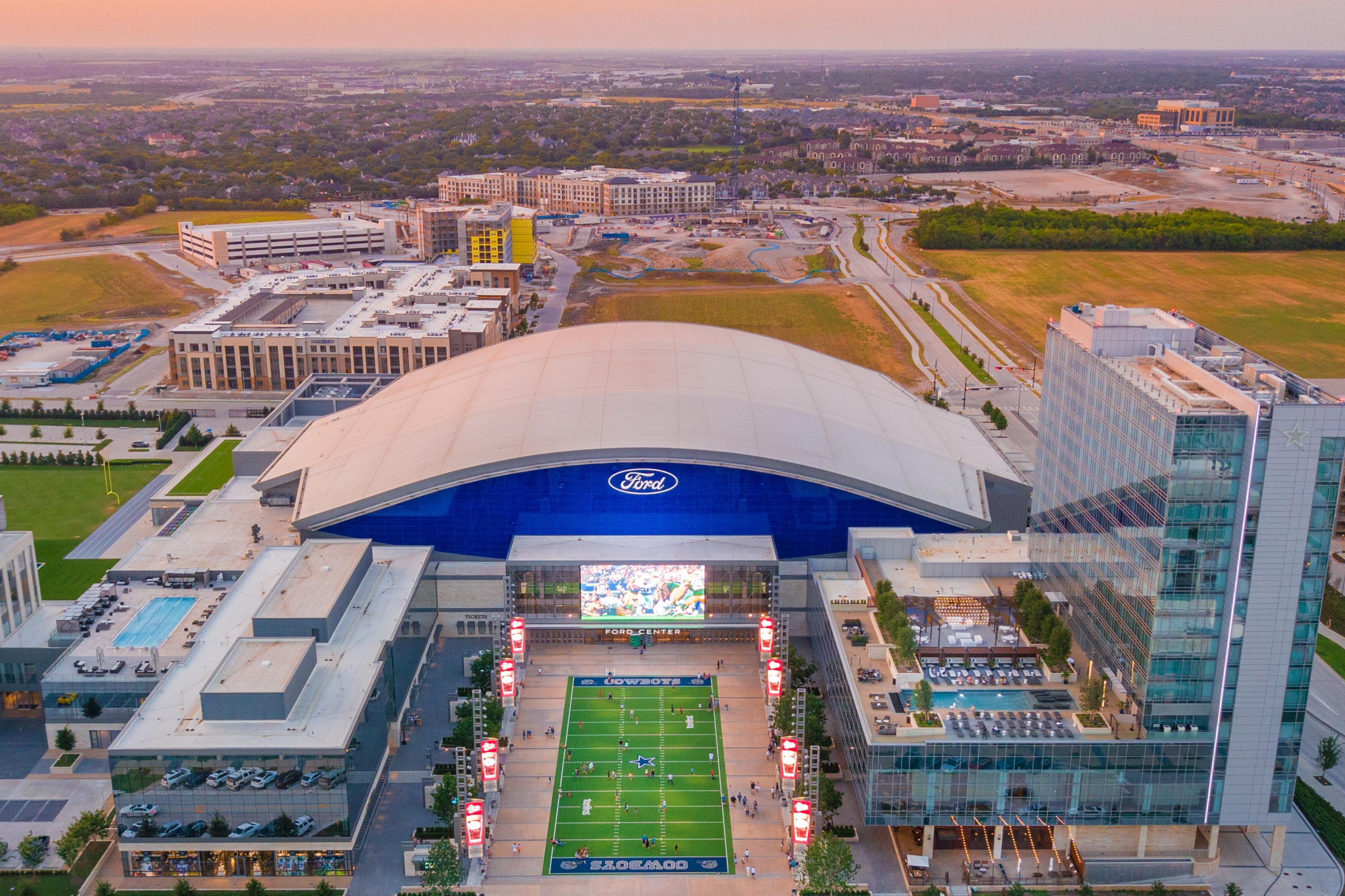 Aerial photo of Ford Center at The Star, Omni Frisco Hotel and Tostito's Plaza. There are hotels under construction in the background.