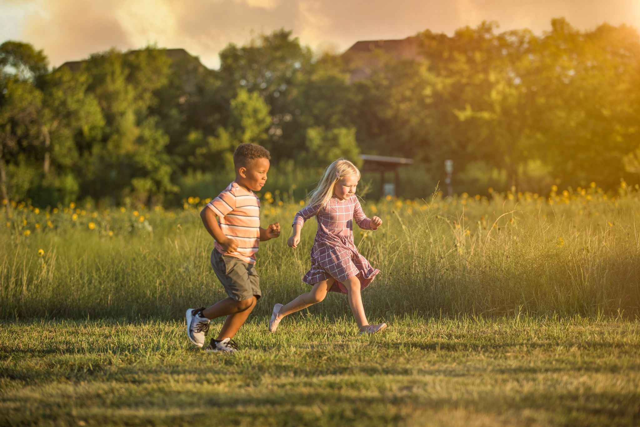 Two small children run through a field.