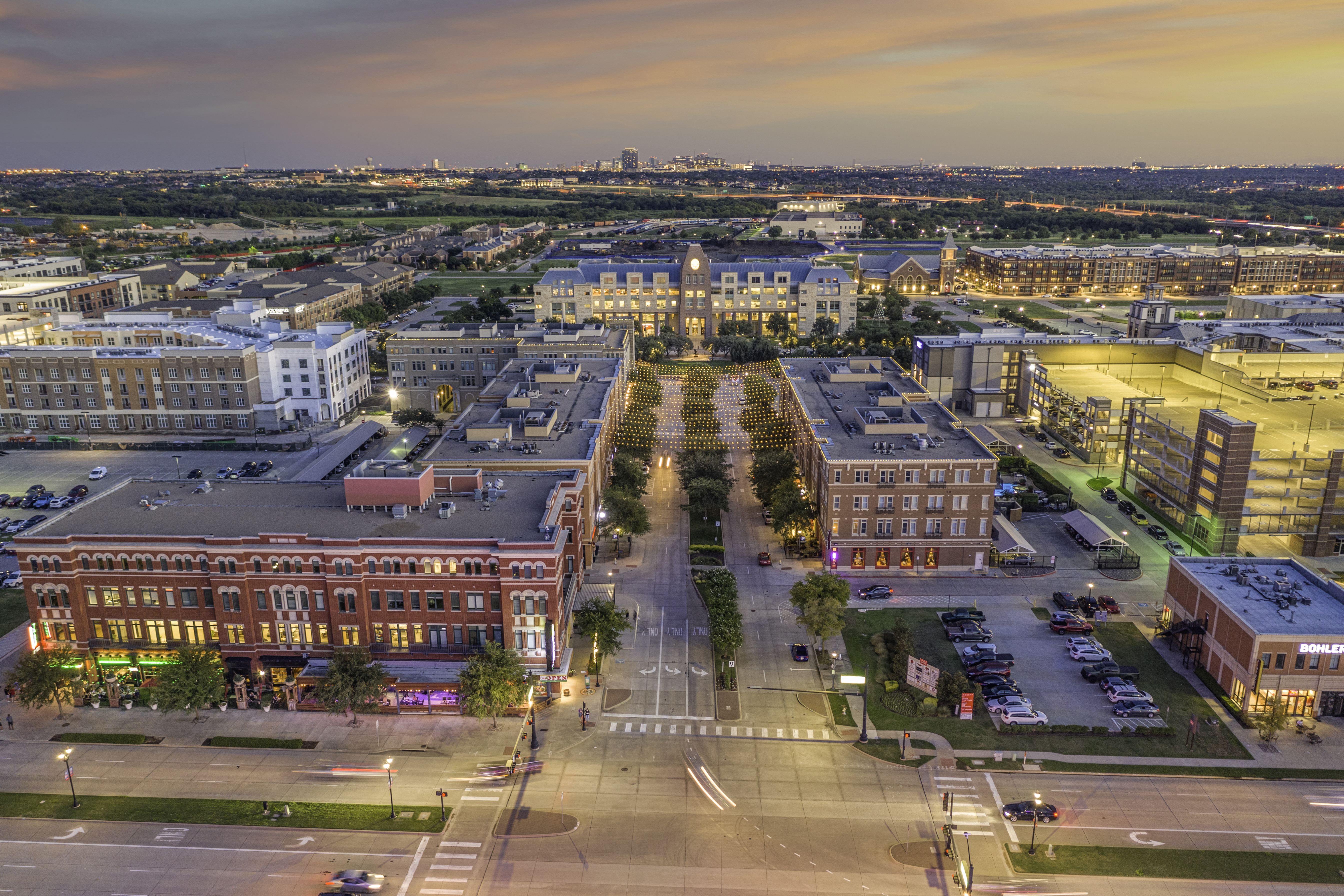 Aerial shot at dusk of four-story buildings and City Hall in the background