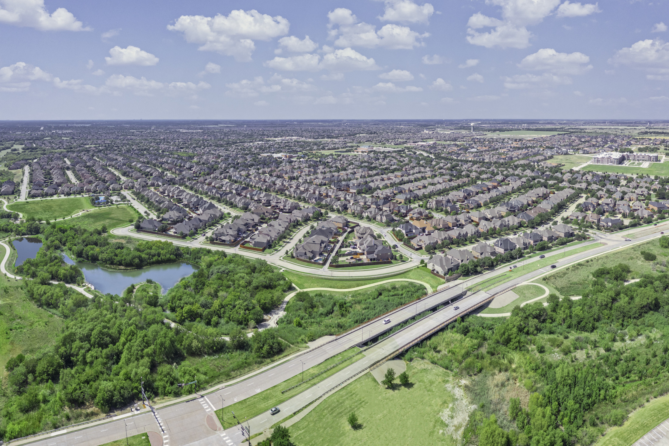 Aerial photo of a large residential neighborhood and and park with bright green grass and walking paths.